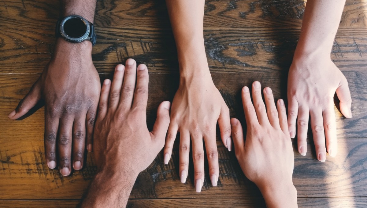 Five hands of different skin tones laid out on a table.