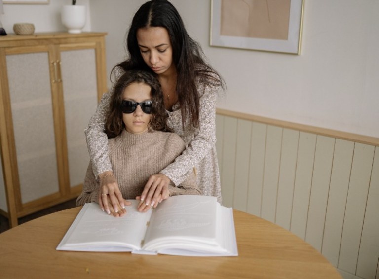 Personal support working helping someone who is blind to read