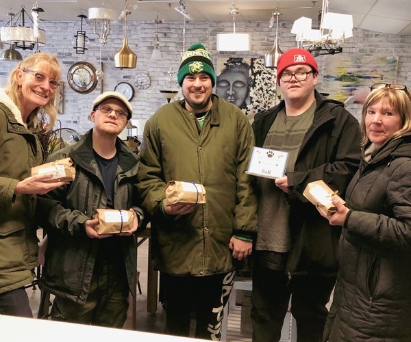 A group of adults holding bags of dog biscuits in a store of one of the CLASS partners
