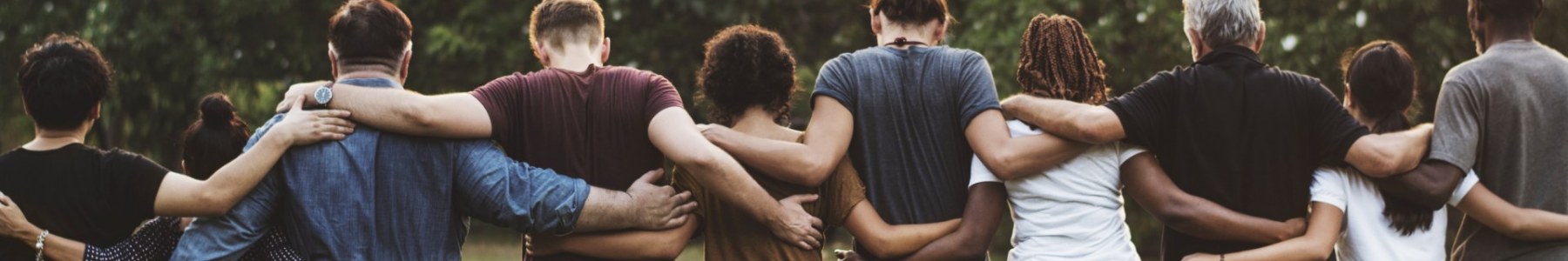 The backs of 9 people of varying ages standing with their arms around each other.